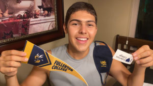 A happy 2020 freshman holds up a Fullerton College pennant and mask