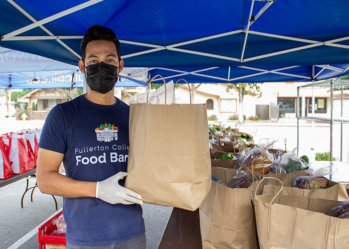 A food bank volunteer holds a bag of groceries.