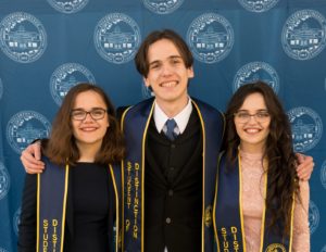 The DeVries triplets stand and smile together.